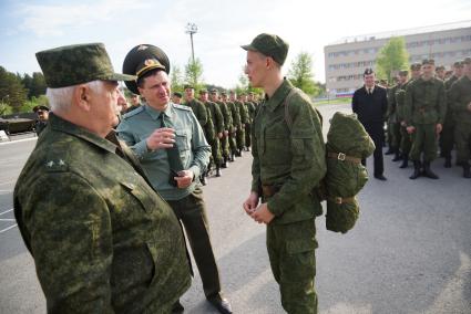 Офицеры разговаривают с новобранцем на плацу.