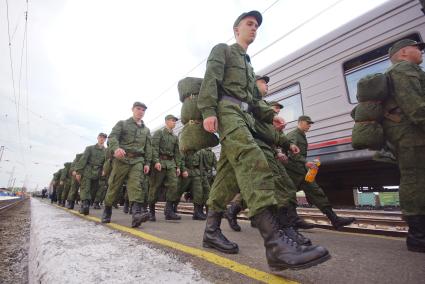 Солдаты призывники строевым шагом идут по перрону вокзала для посадки на поезд.