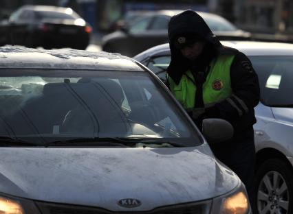 Сотрудник ДПС проверяет документы у водителя автомобиля.