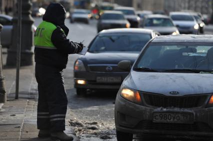 Сотрудник ДПС останавливает водителей автомобилей для проверки документов