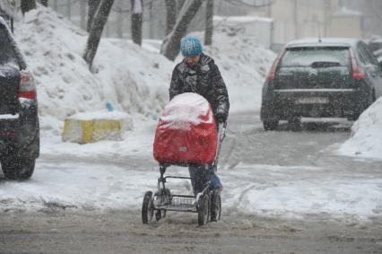 Снегопад. На снимке: женщина с детской коляской.