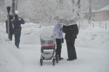 Снегопад. На снимке: женщина с детской коляской на улице города.