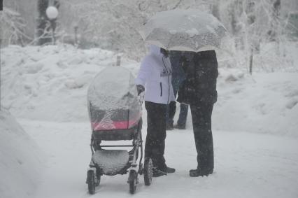 Снегопад. На снимке: женщина с детской коляской на улице города.