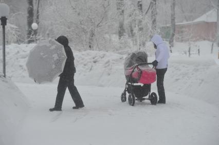 Снегопад. На снимке: женщина с детской коляской на улице города.