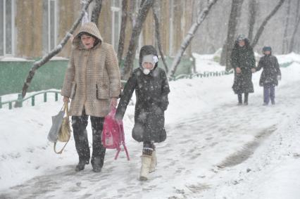 Снегопад. На снимке: женщина несет школьный рюкзак.