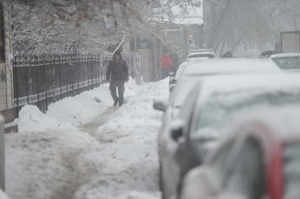 Снегопад. На снимке:  машины в снегу припаркованные у обочины дороги.