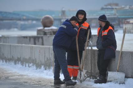 В ЦПКиО им.Горького по набережной идет молодая пара, вслед которой смотрит группа гастарбайтеров.