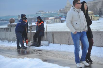 В ЦПКиО им.Горького по набережной идет молодая пара, вслед которой смотрит группа гастарбайтеров.