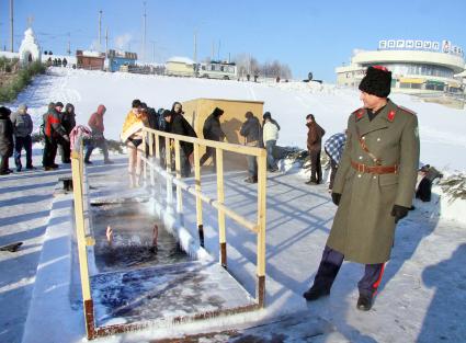 Девушка в купальнике окунается зимой в прорубь во время празднования христианского праздника крещение.