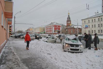 Снежная лавина обрушилась с крыши дома на тротуар и припаркованные автомобили в Барнауле. На снимке: люди у засыпанных снегом поврежденных автомобилей.