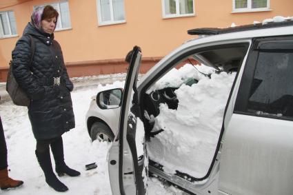 Снежная лавина обрушилась с крыши дома на тротуар и припаркованные автомобили в Барнауле. На снимке: женщина стоит у поврежденного автомобиля засыпанного снегом.