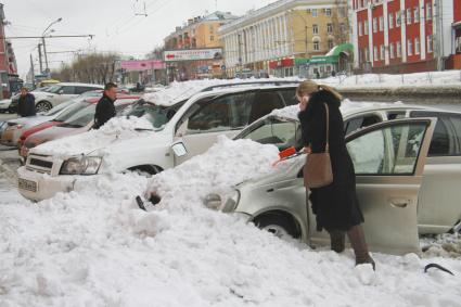 Снежная лавина обрушилась с крыши дома на тротуар и припаркованные автомобили в Барнауле. На снимке: люди стоят у поврежденных автомобилей засыпанных снегом.