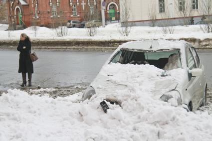 Снежная лавина обрушилась с крыши дома на тротуар и припаркованные автомобили в Барнауле. На снимке: девушка на фоне засыпанного снегом поврежденного автомобиля.