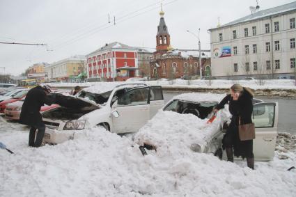 Снежная лавина обрушилась с крыши дома на тротуар и припаркованные автомобили в Барнауле. На снимке: люди стоят у поврежденных автомобилей засыпанных снегом.