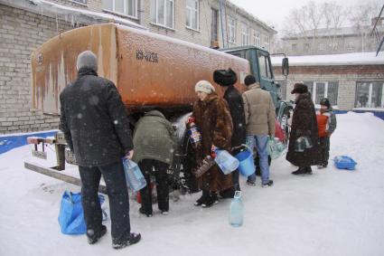 Аварийное отключение воды. На снимке: люди стоят с ведрами вокруг поливочной машины.