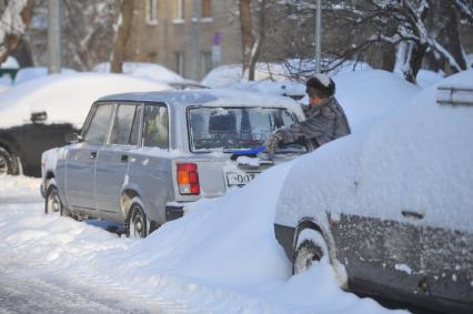 Последствия снегопада. На снимке: женщина чистит автомобиль от снега.