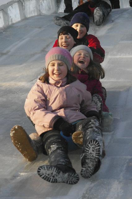 Дети катаются на ледяной горке.