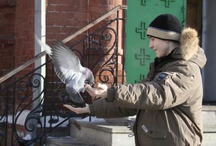 Подросток кормит голубей с рук.
