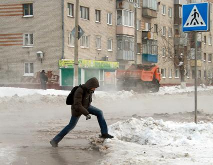 Коммунальная авария. Потоки воды идут по дороге. Пешеход перепрыгивает через поток.