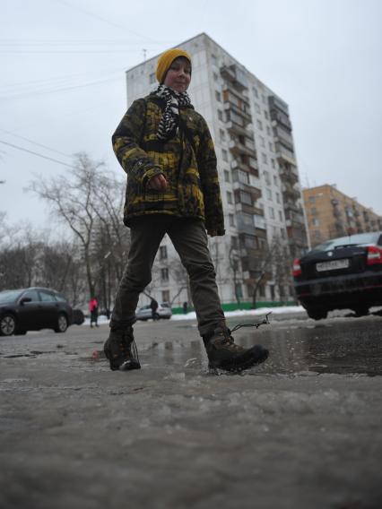 Подросток идет по лужам