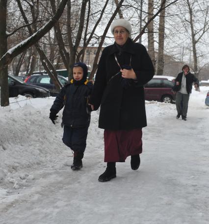 Женщина с ребенком идут по скользкому тротуару.