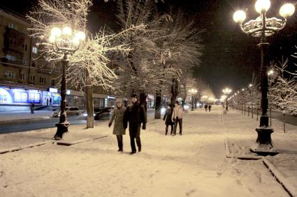 Люди гуляют по зимнему вечернему городу.