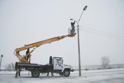 Электрик устраняет обрыв проводов во время сильного снегопада.