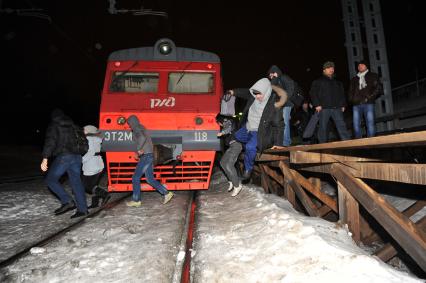 Безбилетные пассажиры электропоезда спрыгивают с платформы на железнодорожной станции  `Петровско-Разумовское`.