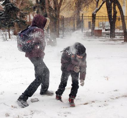 Дети зимой на улице играют в снежки.