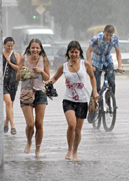 Люди бегут по улице под проливным дождем.