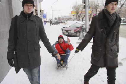 Два парня везут на санках третьего.