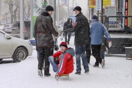 Два парня везут на санках третьего.