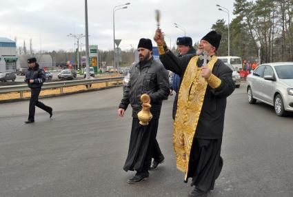 В Воронеже освятили одно из самый аварийных мест города - кольцо на улице Антонова-Овсеенко. На снимке: священник идет по дороге, освящая ее с помощью святой воды.