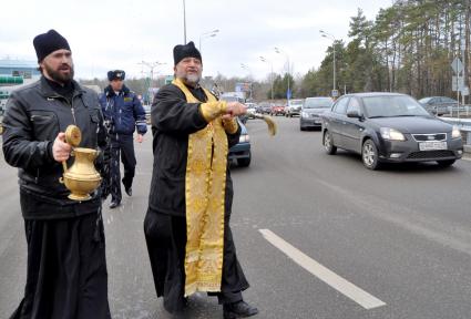 В Воронеже освятили одно из самый аварийных мест города - кольцо на улице Антонова-Овсеенко. На снимке: священник идет по дороге, освящая ее с помощью святой воды.