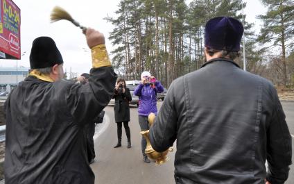 В Воронеже освятили одно из самый аварийных мест города - кольцо на улице Антонова-Овсеенко. На снимке: священник идет по дороге, освящая ее с помощью святой воды.