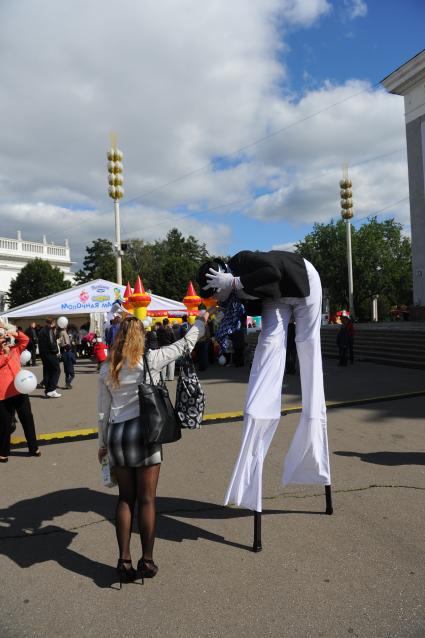 Всероссийский выставочный центр. День города. На снимке: аниматор на ходулях целует девушке руку.