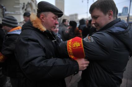 Казанский вокзал. Дружинники совместно с сотрудниками ФМС проводят рейд по выявлению незаконных мигрантов. На снимке: мужчина надевает повязку дружинника.