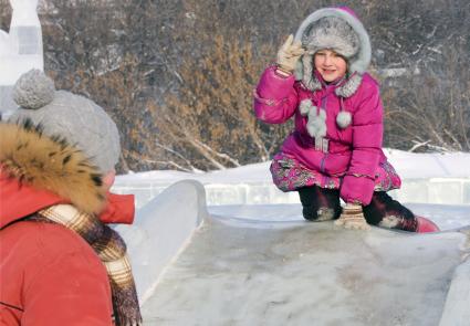 Детский ледовый городок. На снимке: ребенок на ледяной горке.