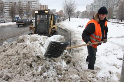 Дворник убирает снег с цлицы.