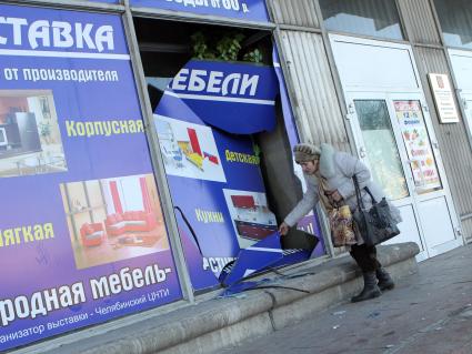 Последствия падения метеорита. Женщина осматривает разбитую витрину магазина в Челябинске.