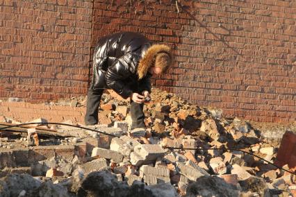 Последствия падения метеорита. Мужчина что-то ищет на груде кирпичей разрушенного фасада завода в Челябинске.