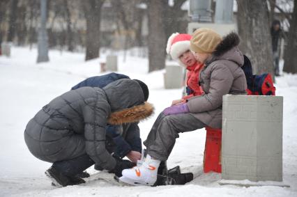 Парк `Сокольники`. Каток. На снимке: родители надевают детям коньки.