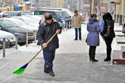 Последствия снегопада. На снимке: дворник убирает снег.