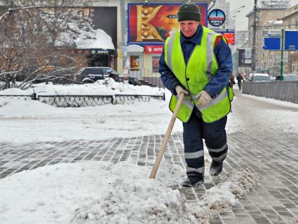 Последствия снегопада. На снимке: дворник убирает снег.