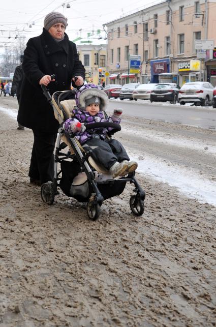 Слякоть. На снимке: женщина с ребенком в прогулочной коляске.