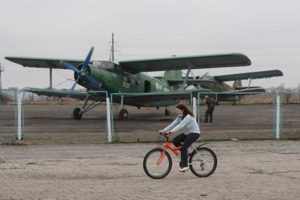 Самолет Ан-2 на аэродроме \"Девау\" в Калининграде, девушка на велосипеде