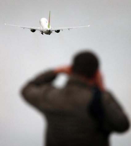 Мужчина фотографирует пассажирский самолет `Боинг 737-800` авиакомпании `S7`.