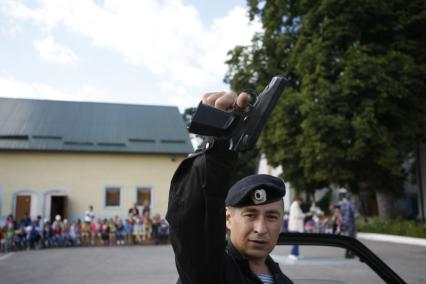 Полицейский в держит пистолет во время учений в детском саду