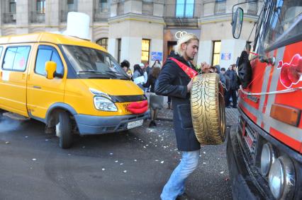 Креативная свадьба 12.12.12. На снимке: молодой человек с автомобильным колесом в руках.