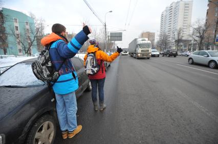 Путешествие автостопом. На снимке: молодые люди голосуют на шоссе.